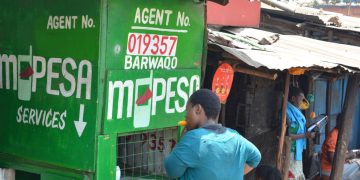 Image of a woman transacting at an MPesa agent shop