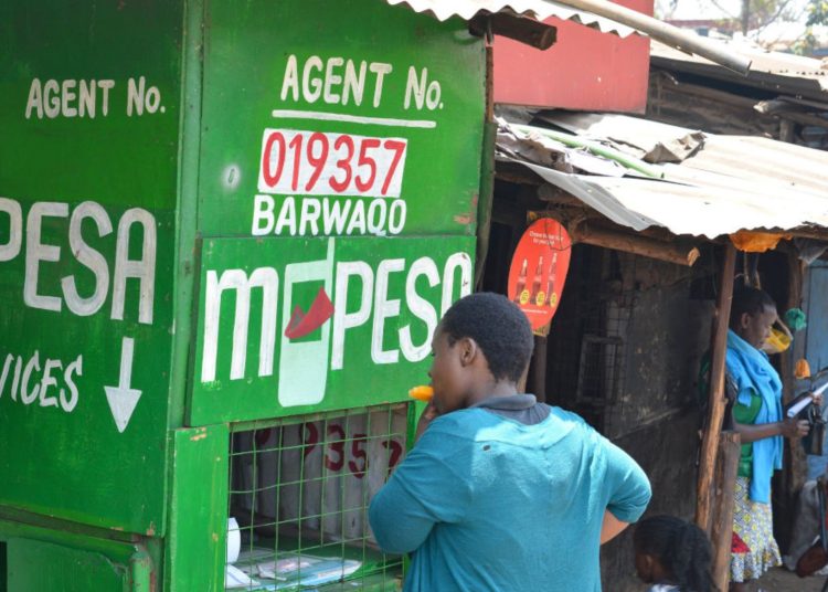 Image of a woman transacting at an MPesa agent shop